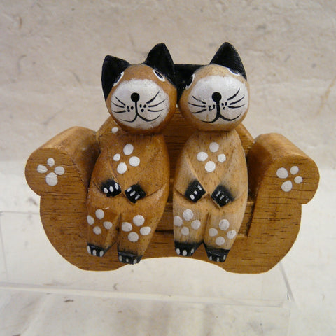 Two Cats Sitting on Natural Wood Sofa decorated with Flowers