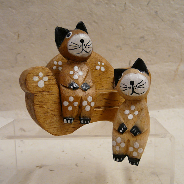 Two Cats Sitting on Natural Wood Sofa decorated with Flowers