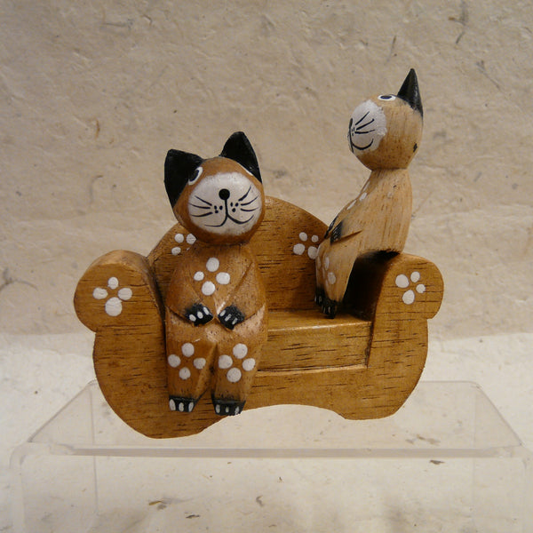 Two Cats Sitting on Natural Wood Sofa decorated with Flowers